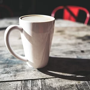 A tall white coffee mug with a Local Jonny's Latte.